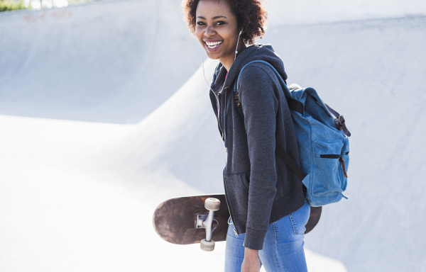 glad ung kvinde med skateboard lytter